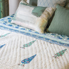 Pea cushion cover pictured on a bed with a Thea cushion cover