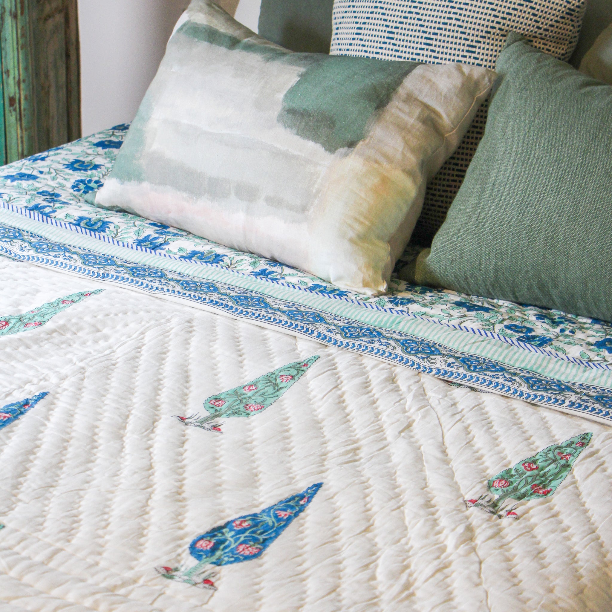 Pea cushion cover pictured on a bed with a Thea cushion cover