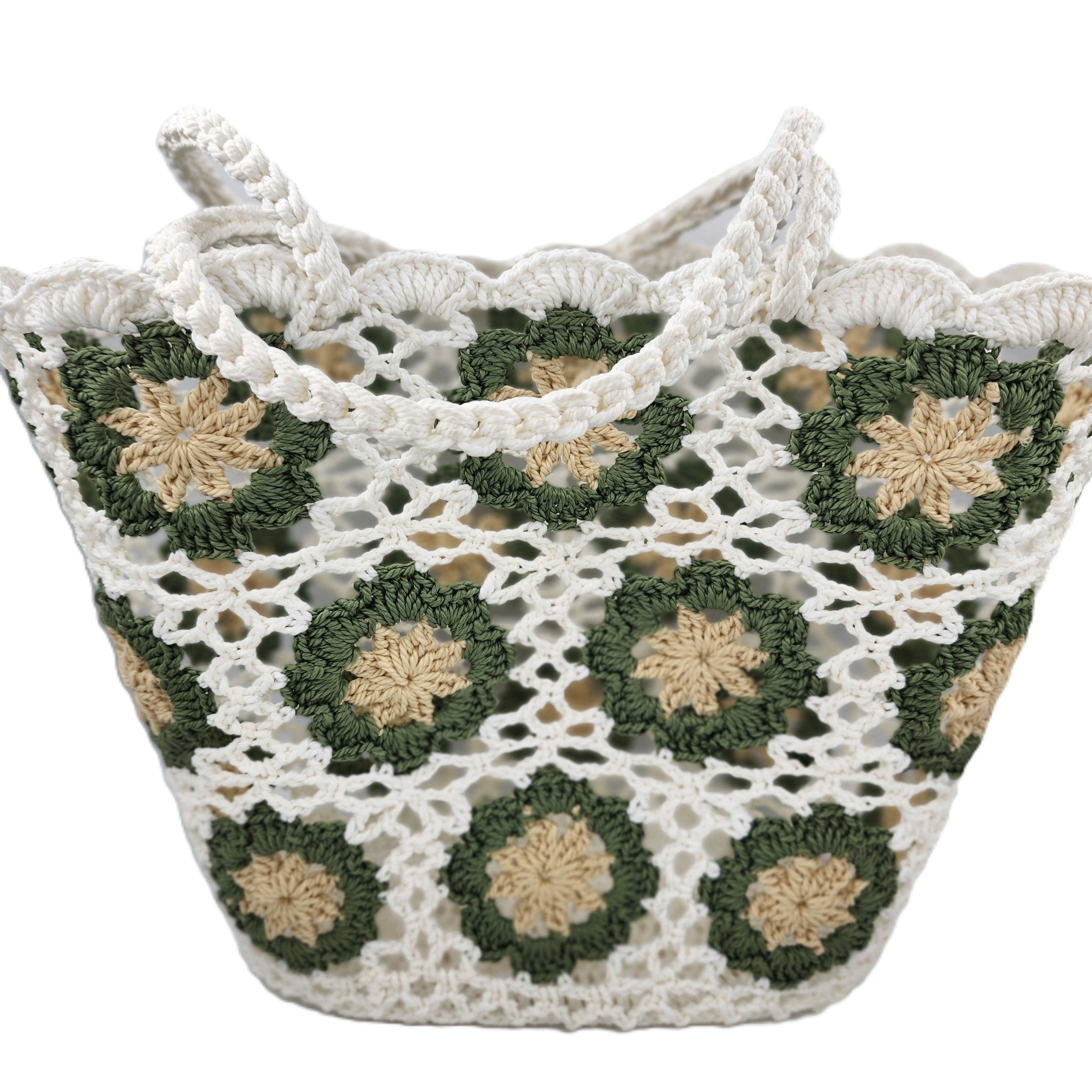 A crocheted tote bag with white lace-like crochet and green floral motifs outlined with beige centers, shown on a plain white background.