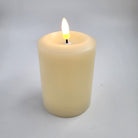 Flameless ivory pillar candle styled inside a glass hurricane lamp