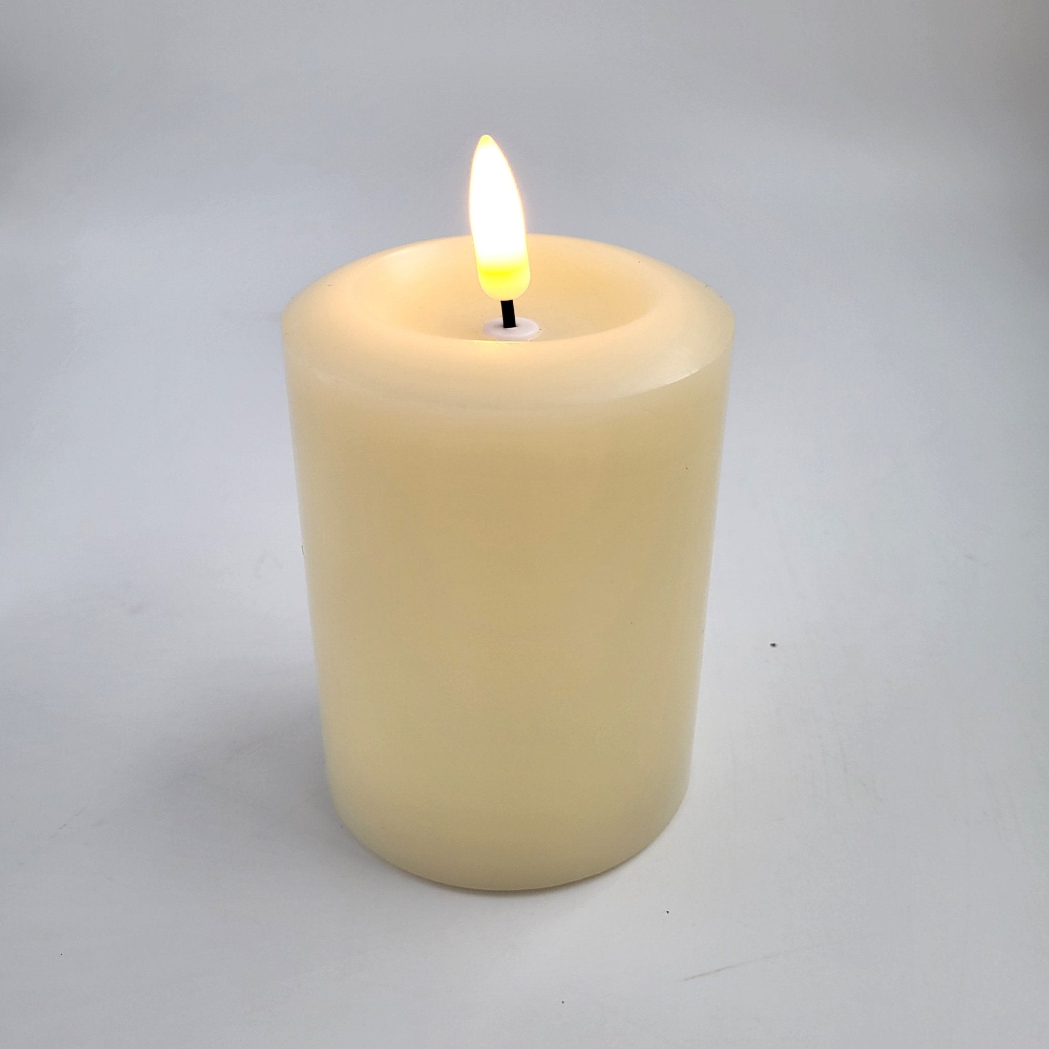 Flameless ivory pillar candle styled inside a glass hurricane lamp