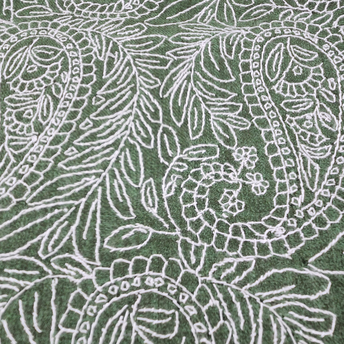 Fine pashmina shawl hand embroidered with a delicate white paisley pattern against a green background.
