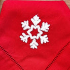 White snowflake on red linen napkin, hand embroidered, detail view