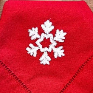 White snowflake on red linen napkin, hand embroidered, detail view