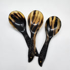 Three decorative rice spoons with glossy black and brown marbled  horn handles and fish-shaped bases, arranged on a plain white background.