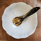 A horn rice spoon with a fish handle in a white Sthal serving bowl on a wooden table