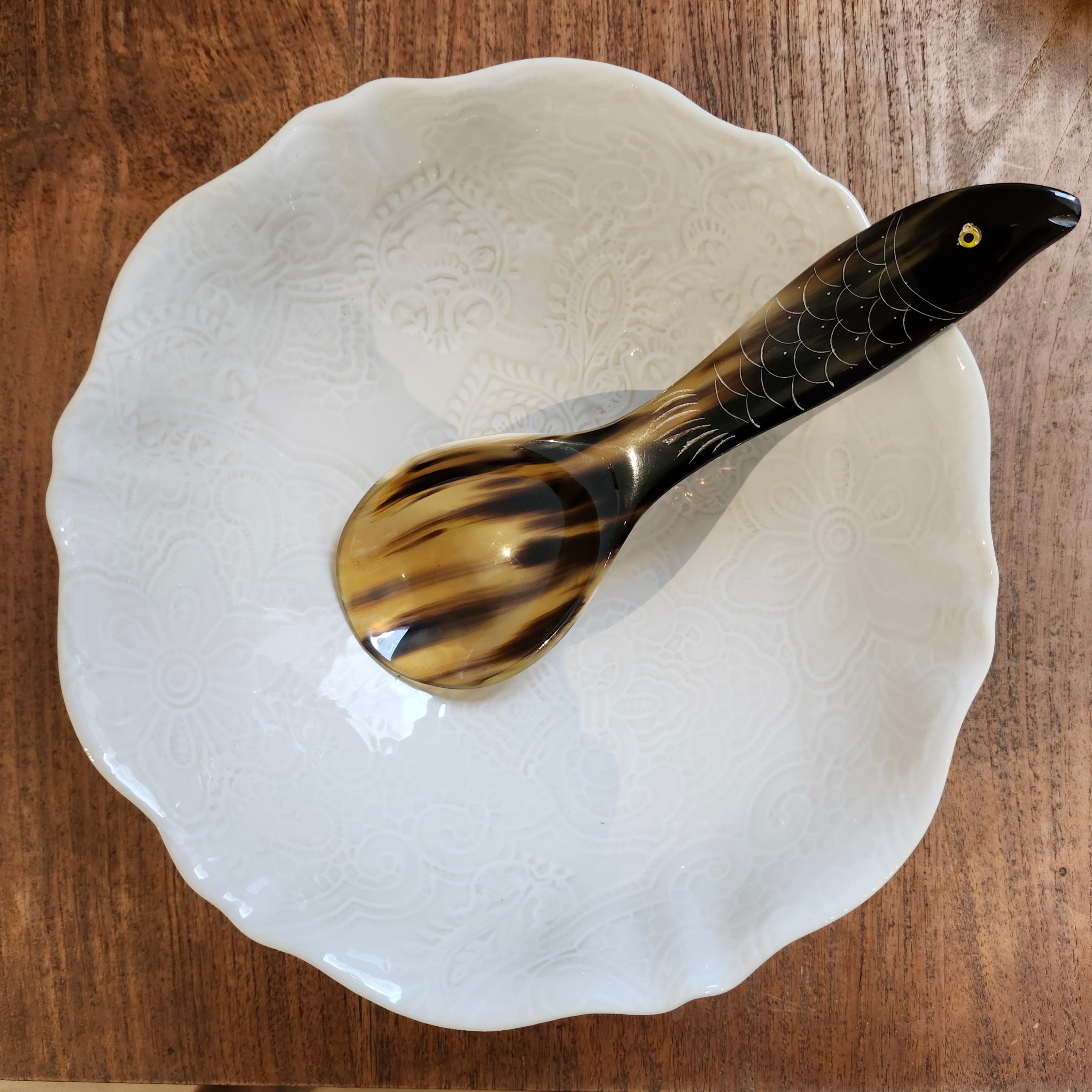 A horn rice spoon with a fish handle in a white Sthal serving bowl on a wooden table