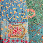 Detail of the blue floral block print patchwork and hand stitching on a kantha single quilt, also used as a tablecloth