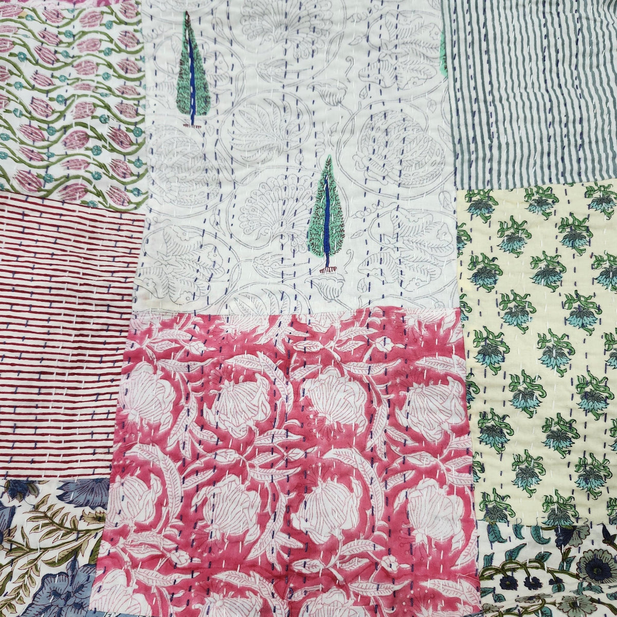 Blue kantha patchwork quilt in floral cotton block prints, with a mauve reverse and two colour stitching.