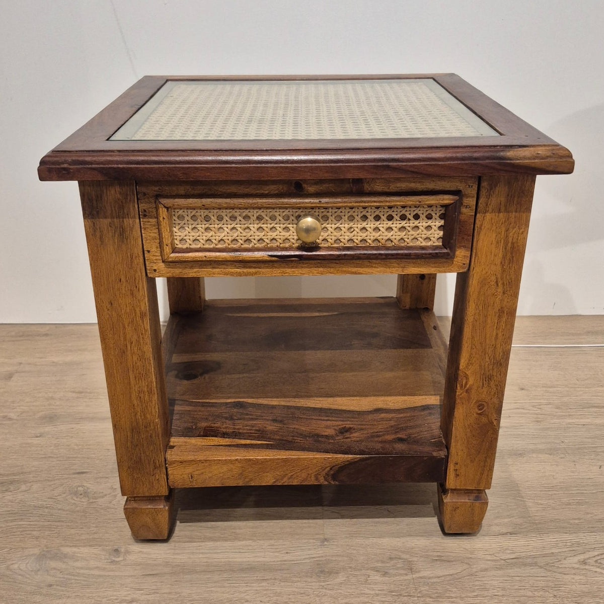 Teak bedside cabinet with a cane top under glass and a cane drawer front with a brass handle, 48cm cubed.