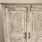 Hand-carved mango wood cupboard with a whitewash finish and floral panels