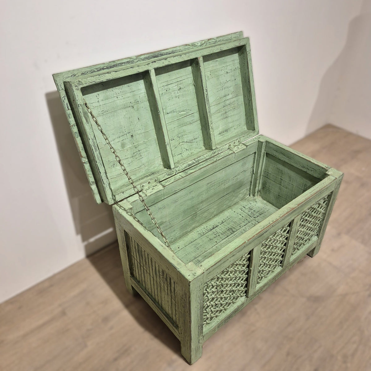 Painted ironwork panel across the front of a pistachio green teak storage chest, made in India, 44 cm deep