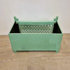 Traces of the original yellow paintwork show beneath the pistachio green on this vintage teak planter