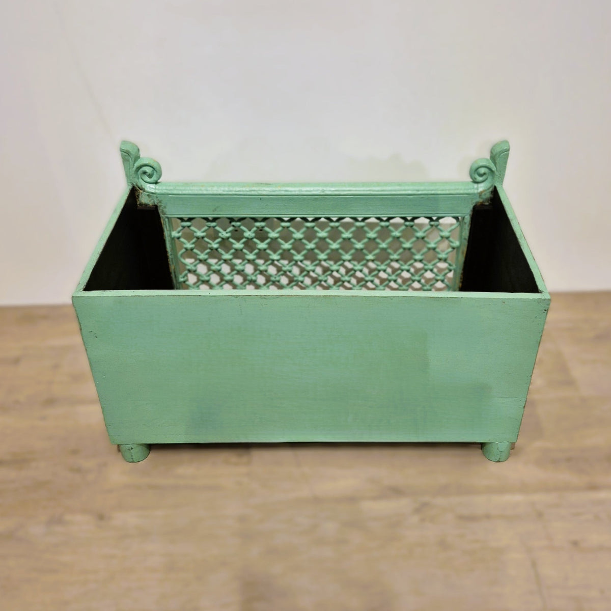 Traces of the original yellow paintwork show beneath the pistachio green on this vintage teak planter