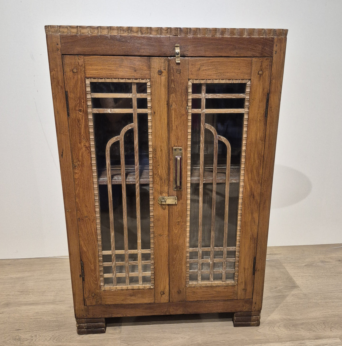 Restored vintage teak cabinet in Art Deco style, with geometric woodwork on the glass doors and brass handles.