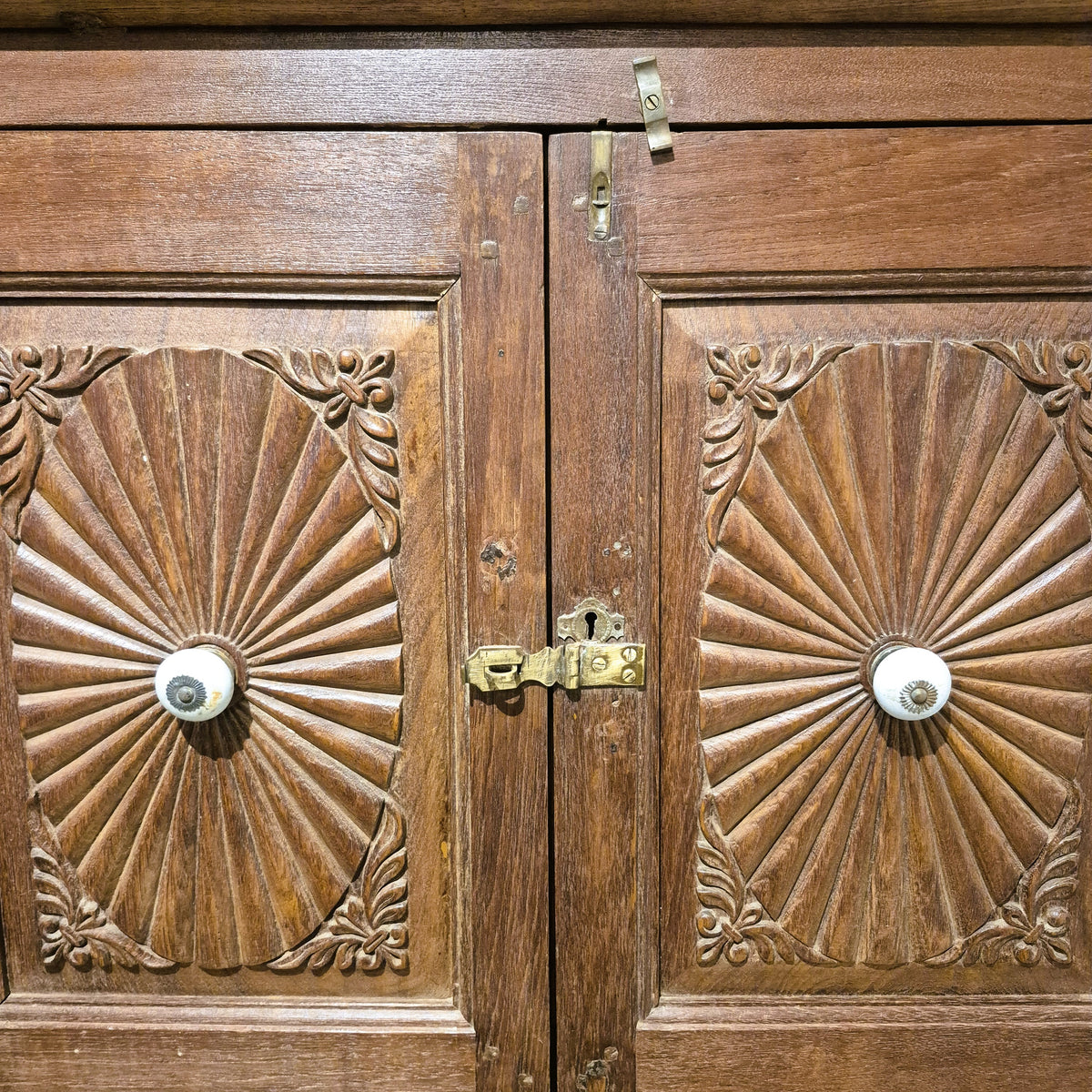 Teak sunburst cabinet with ceramic knobs and two brass handled drawers at the base, 59 cm deep, India