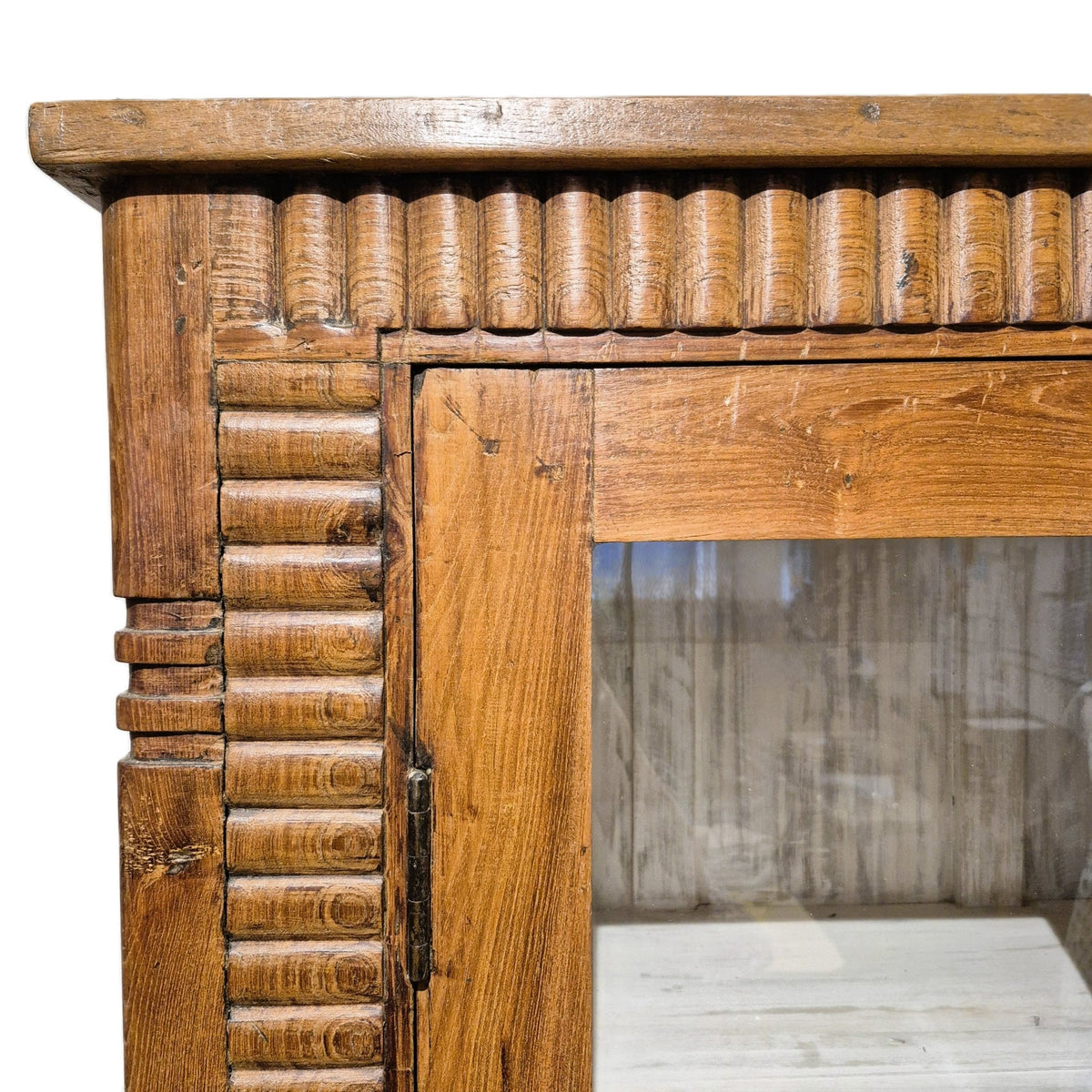 Fluted teak cabinet finished in natural wax, with glass doors opening onto three shelves, made in India