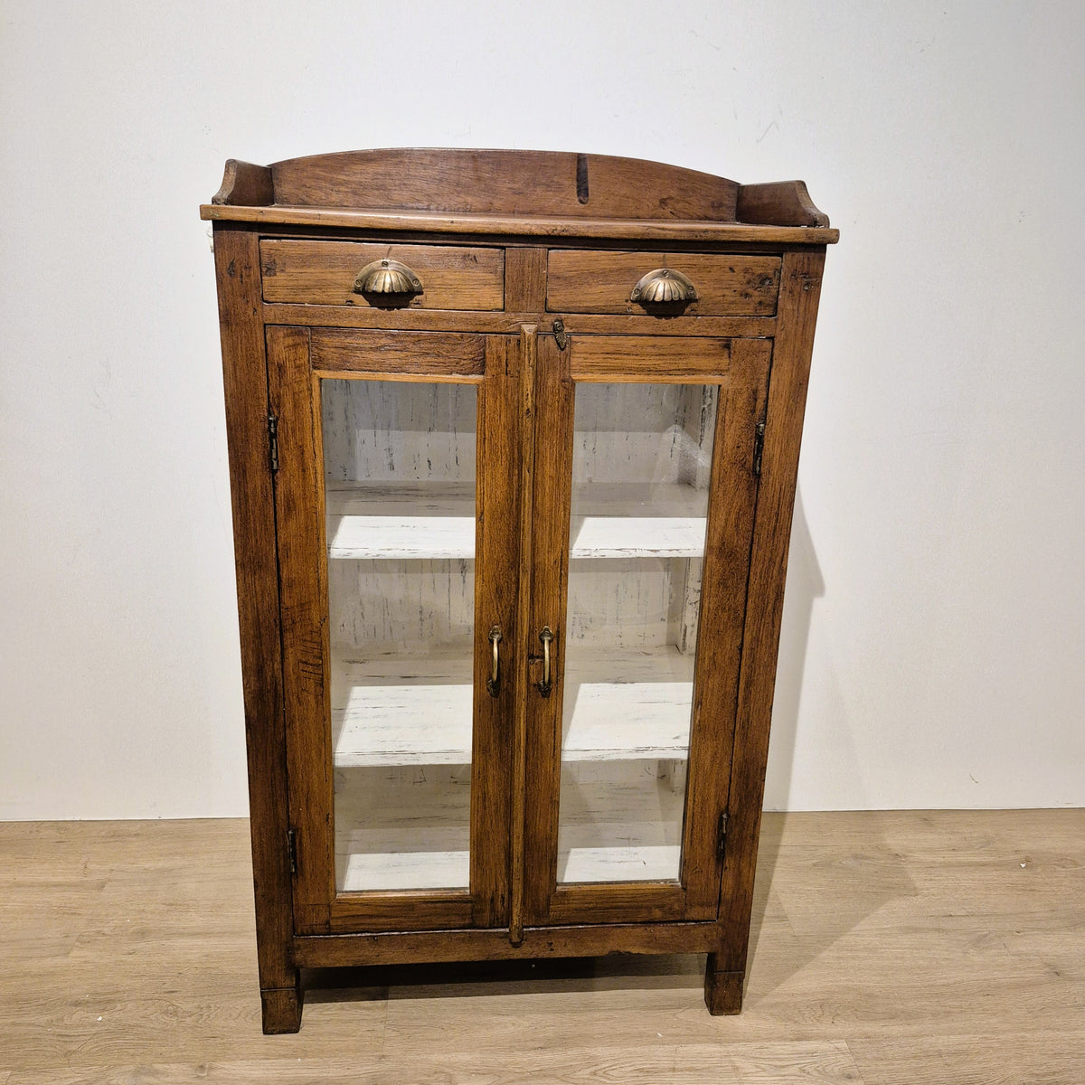 Small glass fronted teak cabinet with two brass handled drawers and three inner shelves, 125 cm high