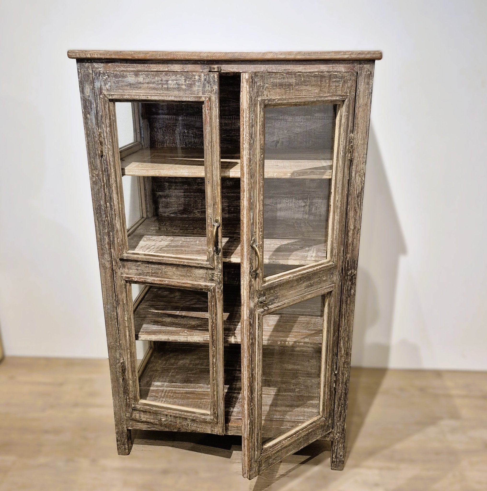 Glass sided teak cabinet with brass handles and three internal shelves, 49 cm deep, 130 cm high, India