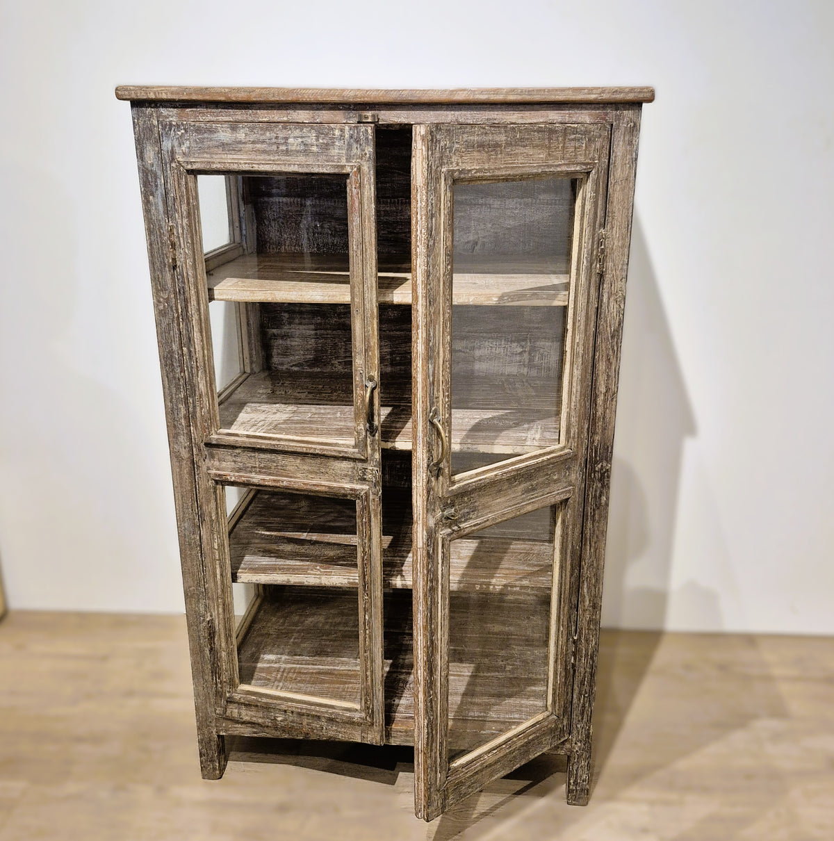 Glass sided teak cabinet with brass handles and three internal shelves, 49 cm deep, 130 cm high, India