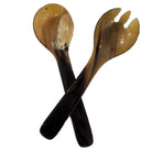 A pair of horn salad servers crossed over each other on a plain white background.