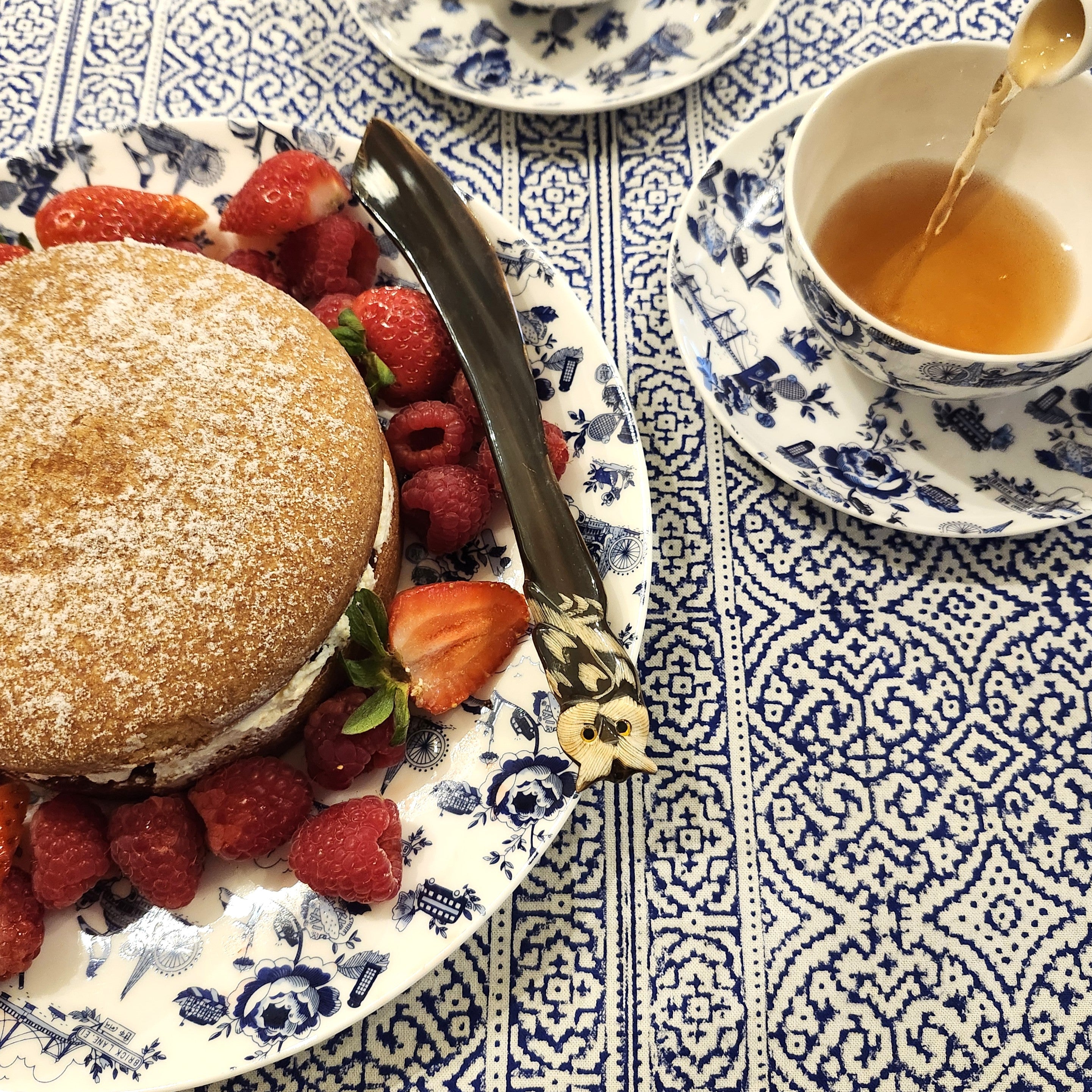Horn cake knife on a plate with a cake and a cup of tea