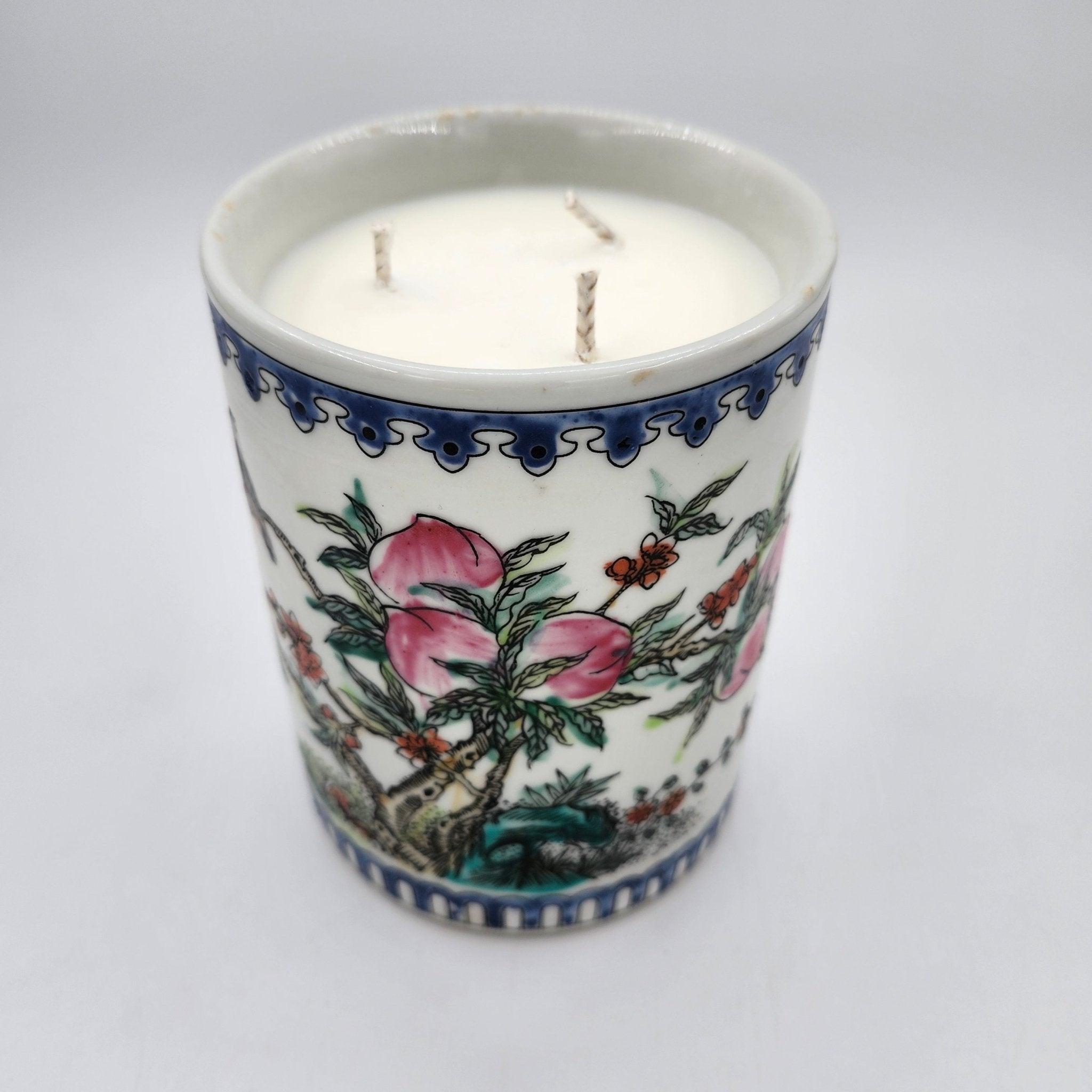 Peaches candle, peach-painted ceramic pot, three wicks, styled view