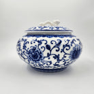 Blue and white ceramic jar with floral pattern containing a scented candle
