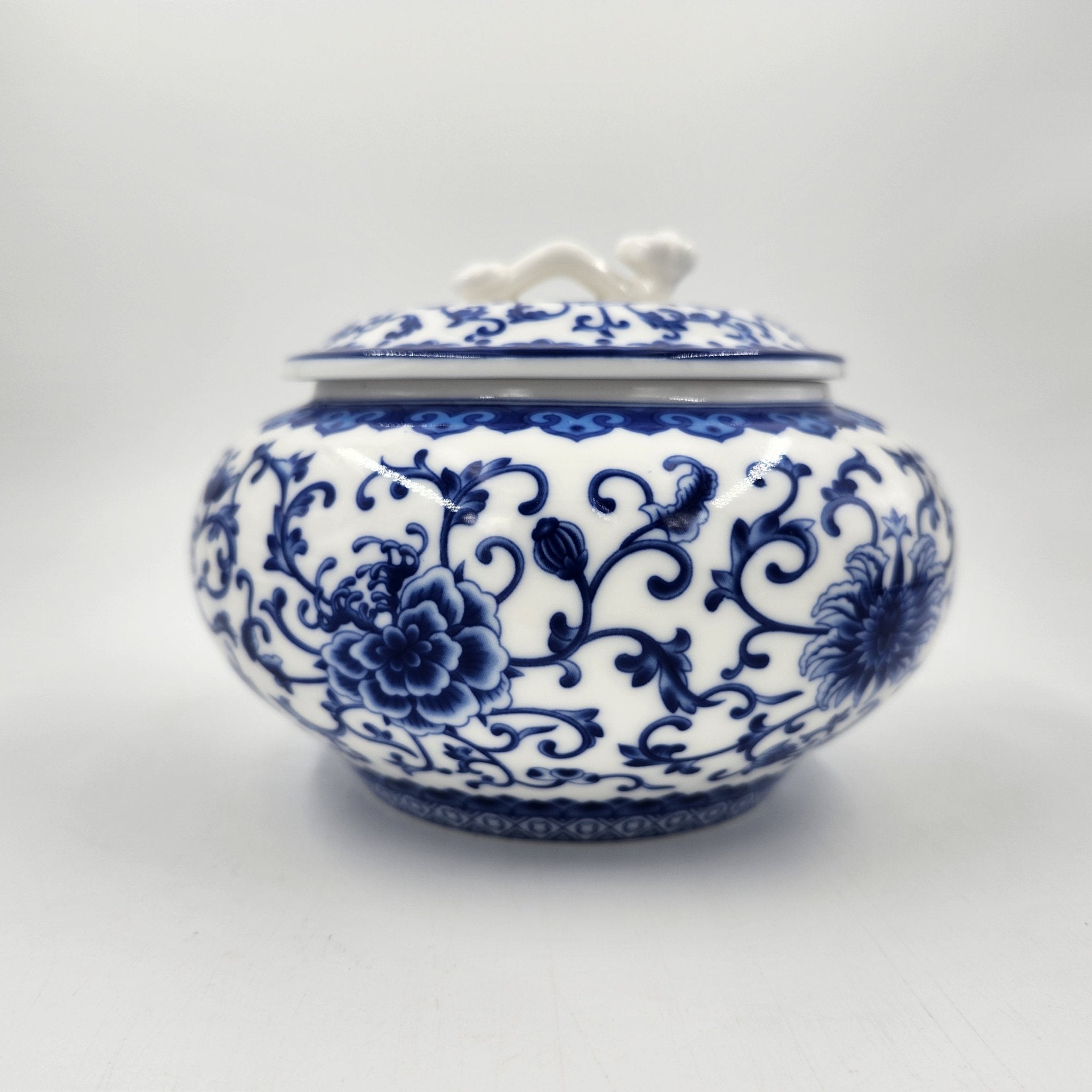 Blue and white ceramic jar with floral pattern containing a scented candle