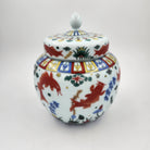 Scented candle in a decorative ceramic jar with golden koil colourful designs on a white background