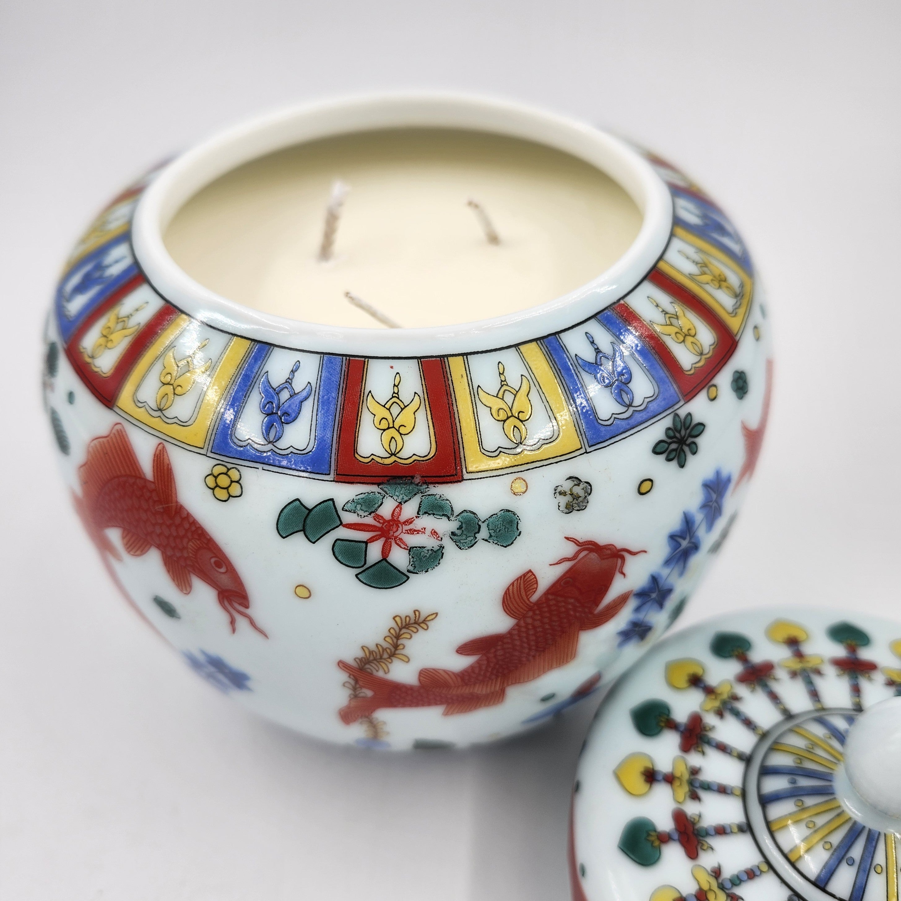 Decorative ceramic jar with colorful designs and a candle inside on a white background