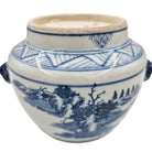 White ceramic jar with blue pine trees and hills patterns containing a scented candle