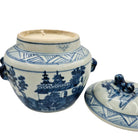 Blue and white ceramic jar with lid containing a scented candle on a white background