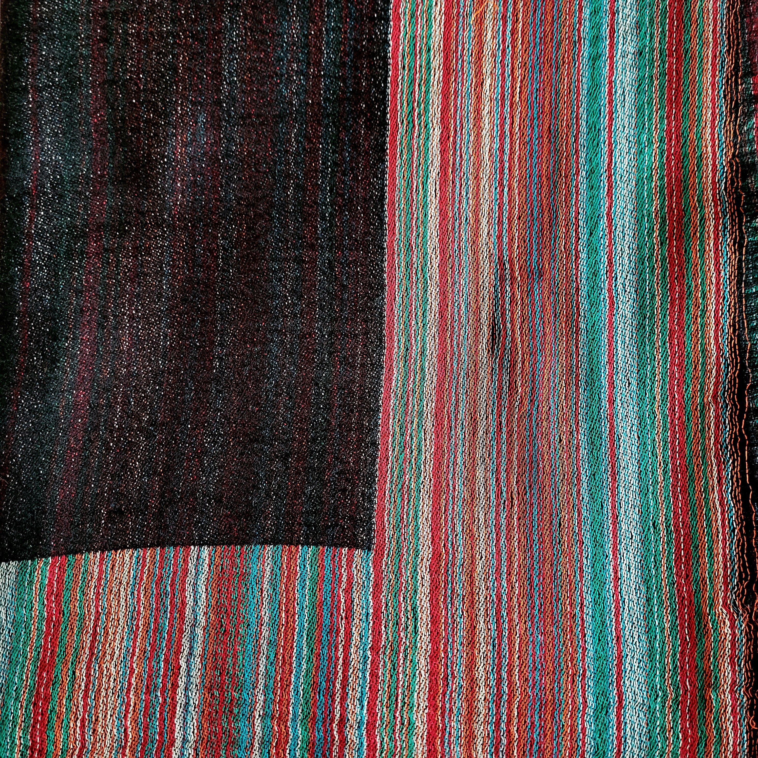 Multi striped pashmina silk shawl in charcoal, one side block colour with a multi striped border, reversed on the other