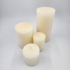 Four off white candles of different sizes 
