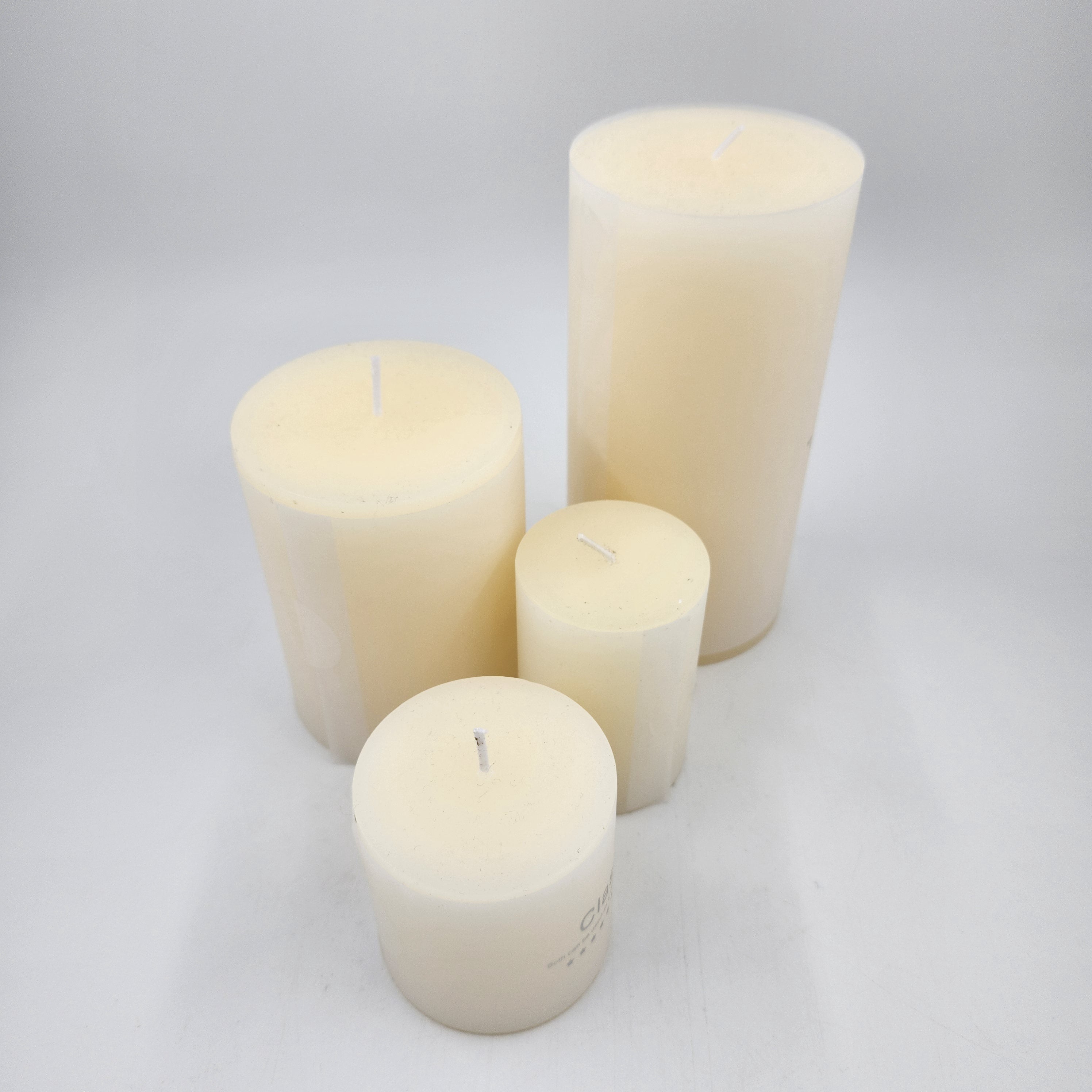 Four off white candles of different sizes 