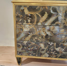Églomisé chest of drawers with gold-leaf glass panels and antiqued brass knobs, styled view