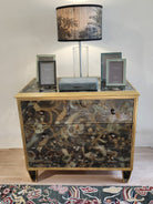 Églomisé chest of drawers detail showing antiqued brass knobs and gilded wood frame, 78.5 x 48 x 72 cm