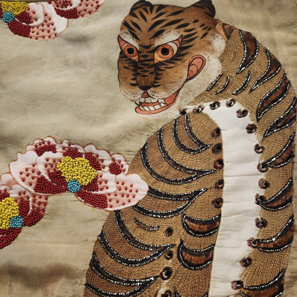 Printed silk cushion cover showing a tiger and pink blossom, highlighted with hand stitched beads, 45cm.