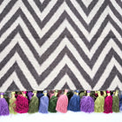 Chevron patterned linen table runner with colorful tassels on a white background