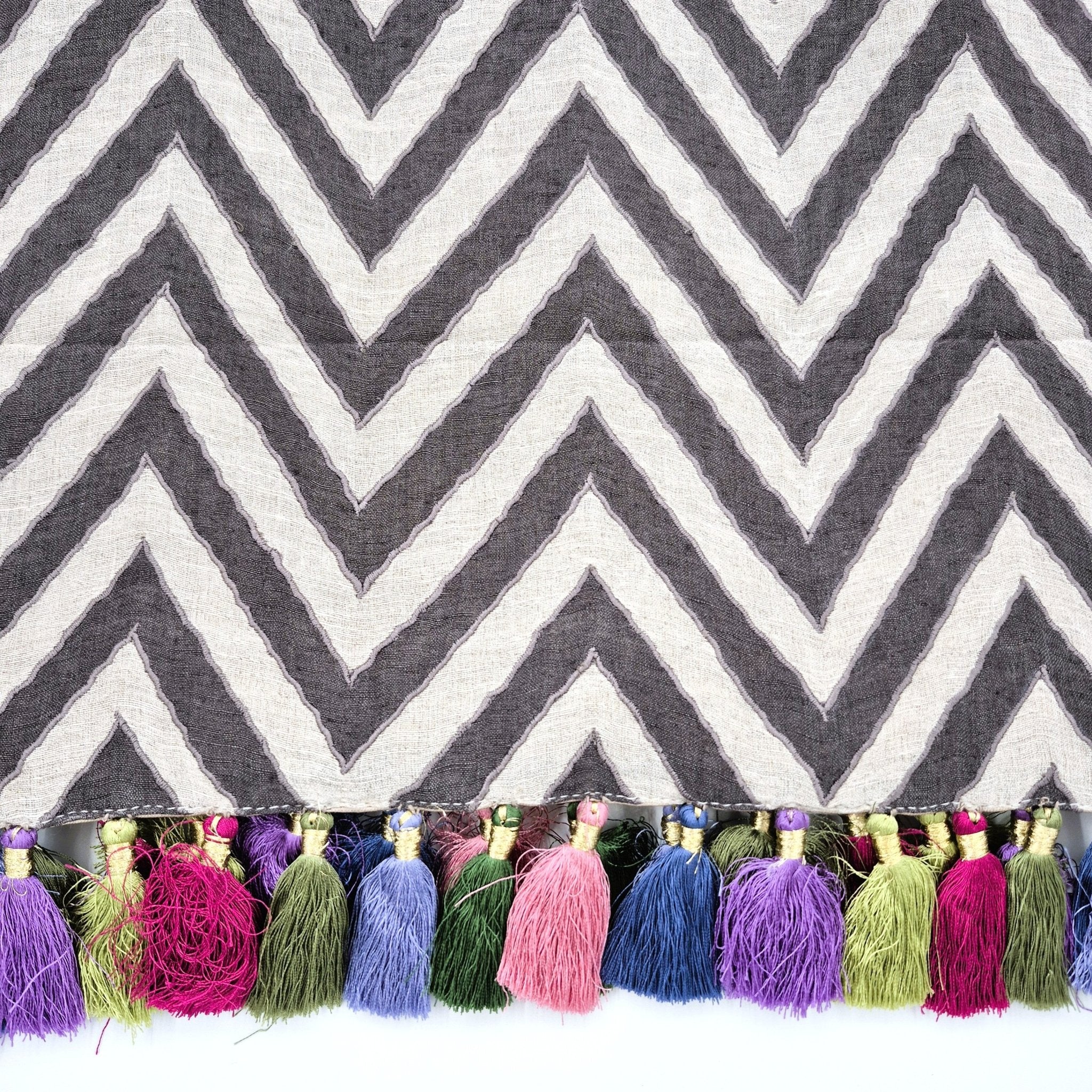 Chevron patterned linen table runner with colorful tassels on a white background