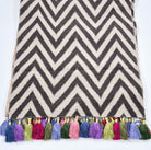 Chevron patterned linen table runner with colorful tassels on a white background