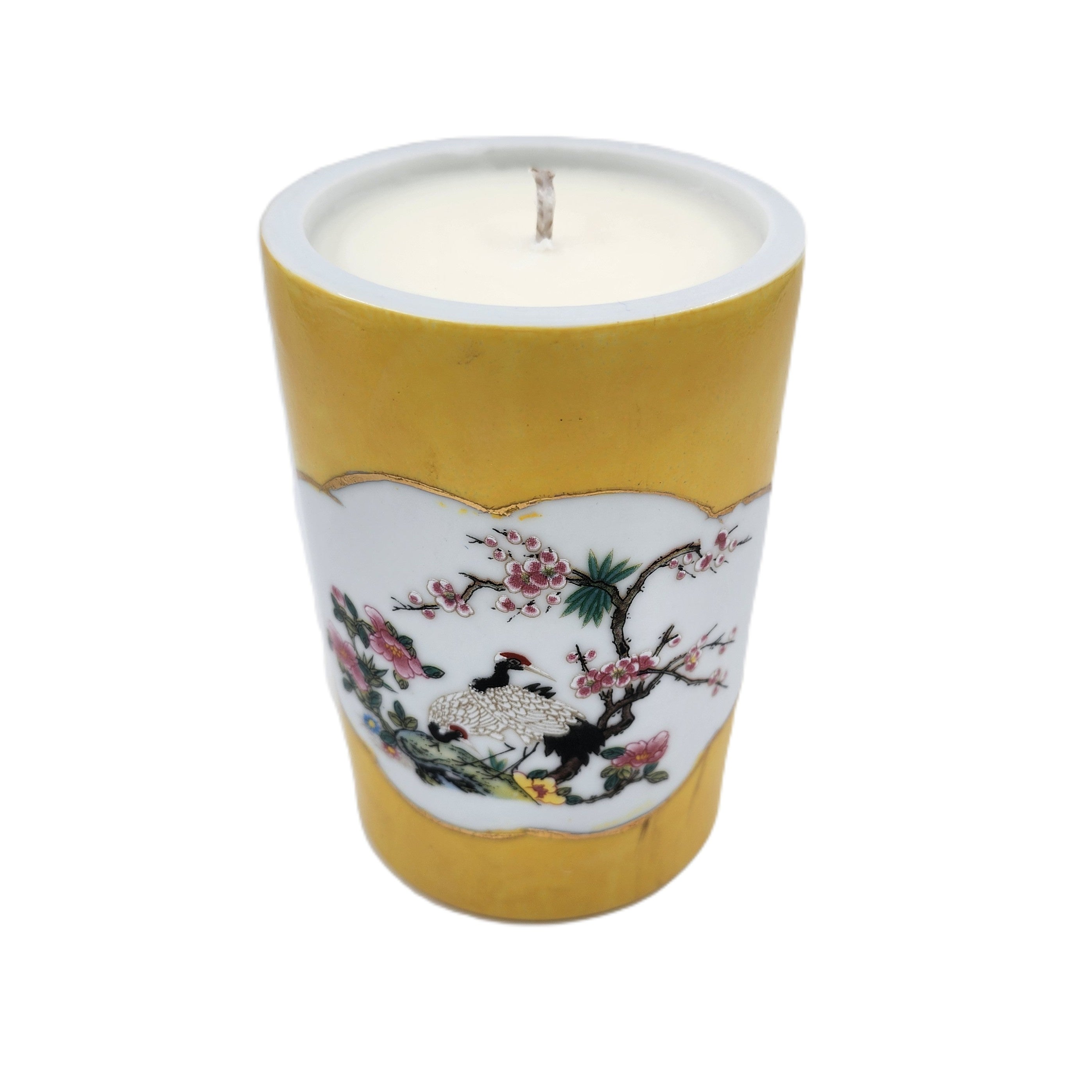 Scented andle in a yellow holder with floral and bird design