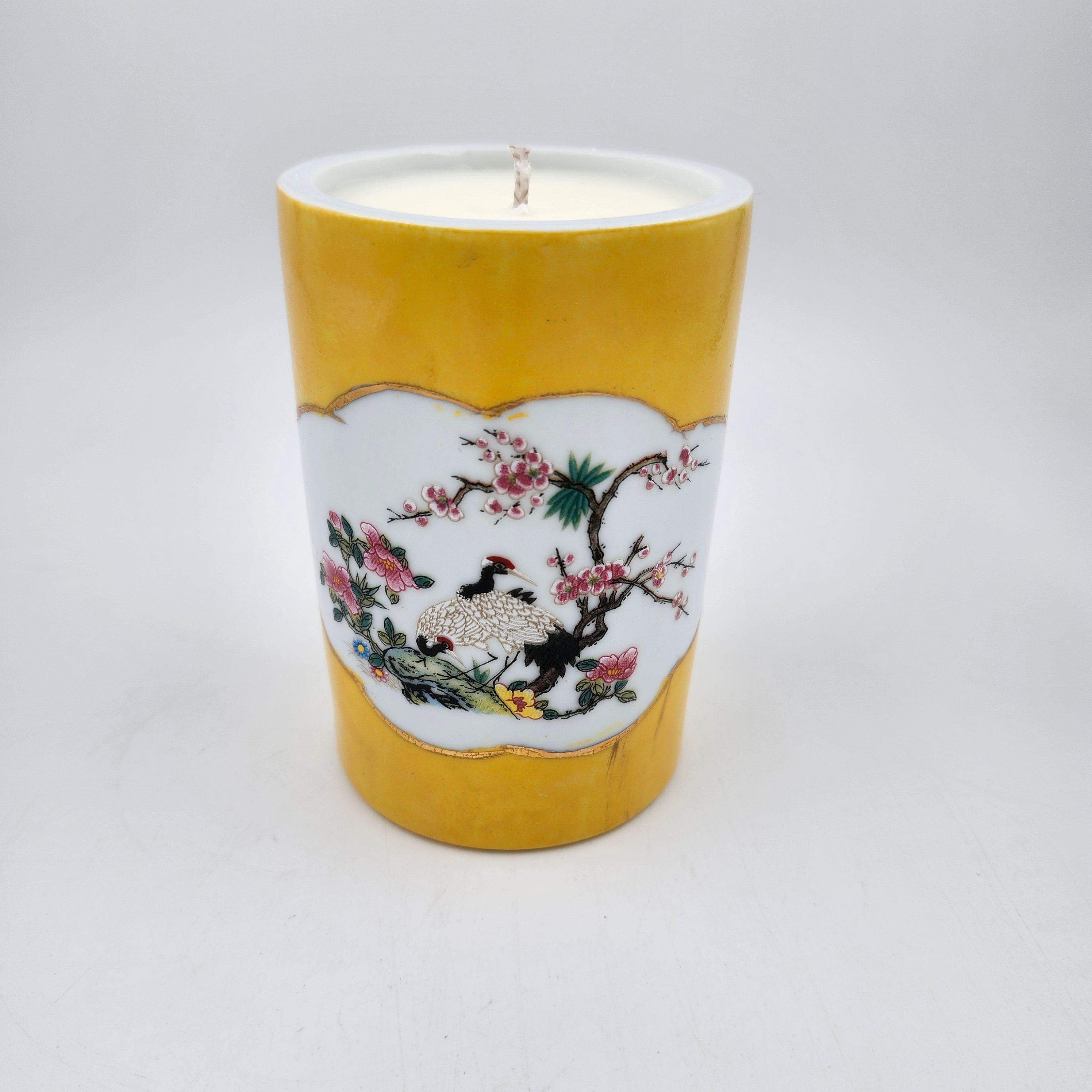 Ceramic scented candle with floral and bird design on a yellow background
