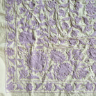 Suzani throw hand embroidered in lavender on a pale green cotton base, used as a tablecloth or bedcover