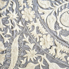 Close-up of intricate hand embroidered suzani floral and paisley patterns on a textured fabric background