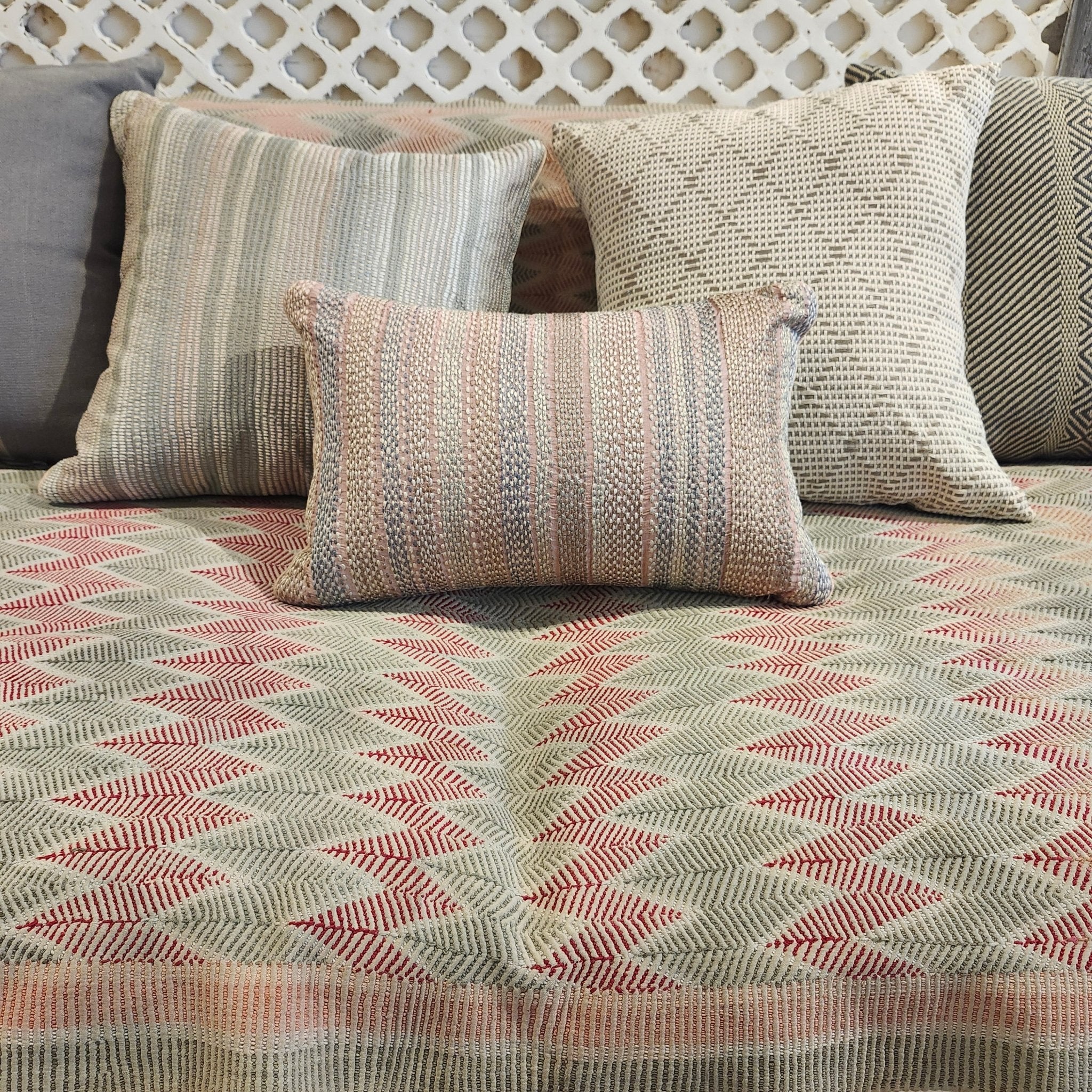 Hand embroidered cushion with shell pink stripes grouped with other cushions on a Zig Zag Vintage Kantha
