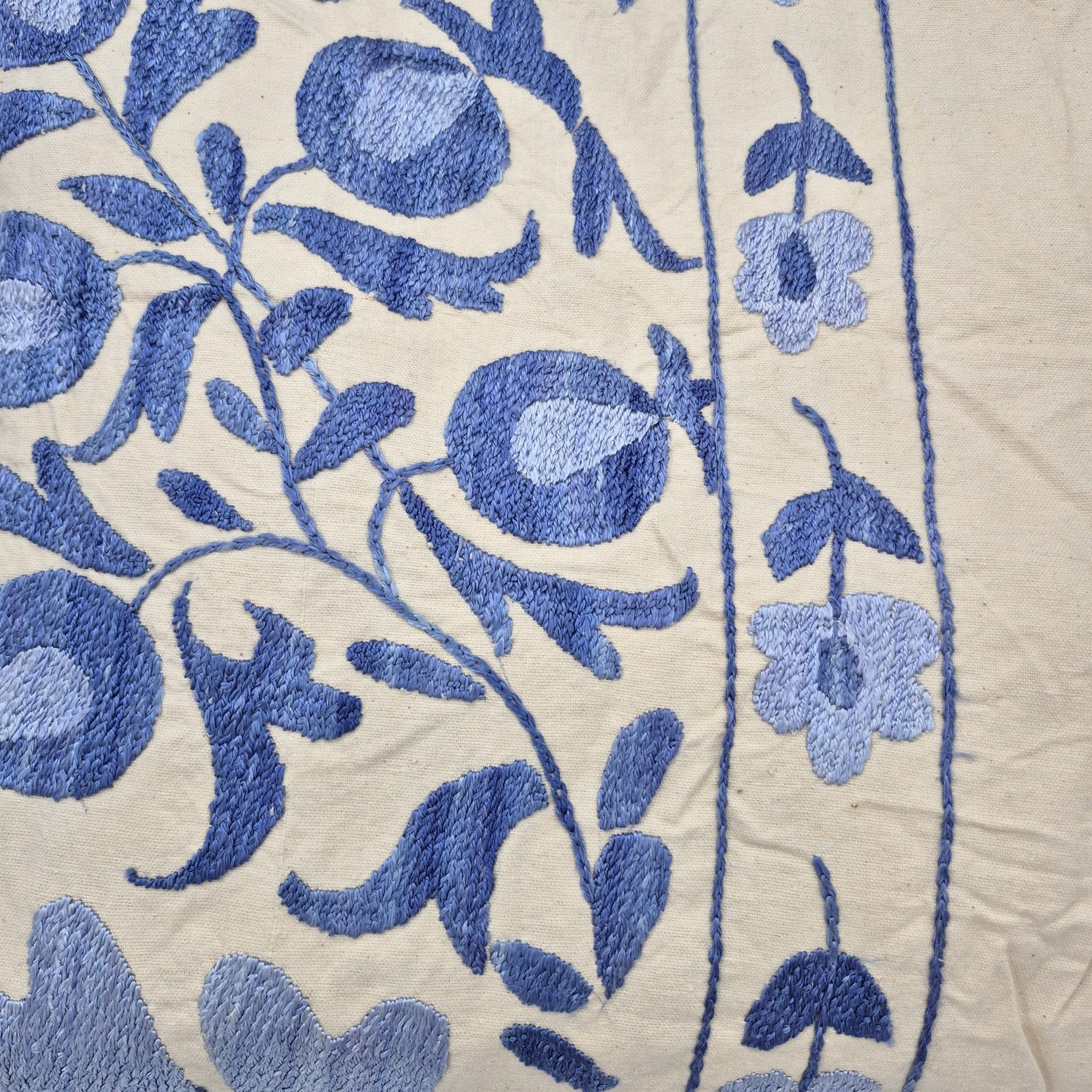 Close-up of blue suzani embroidery on cream fabric