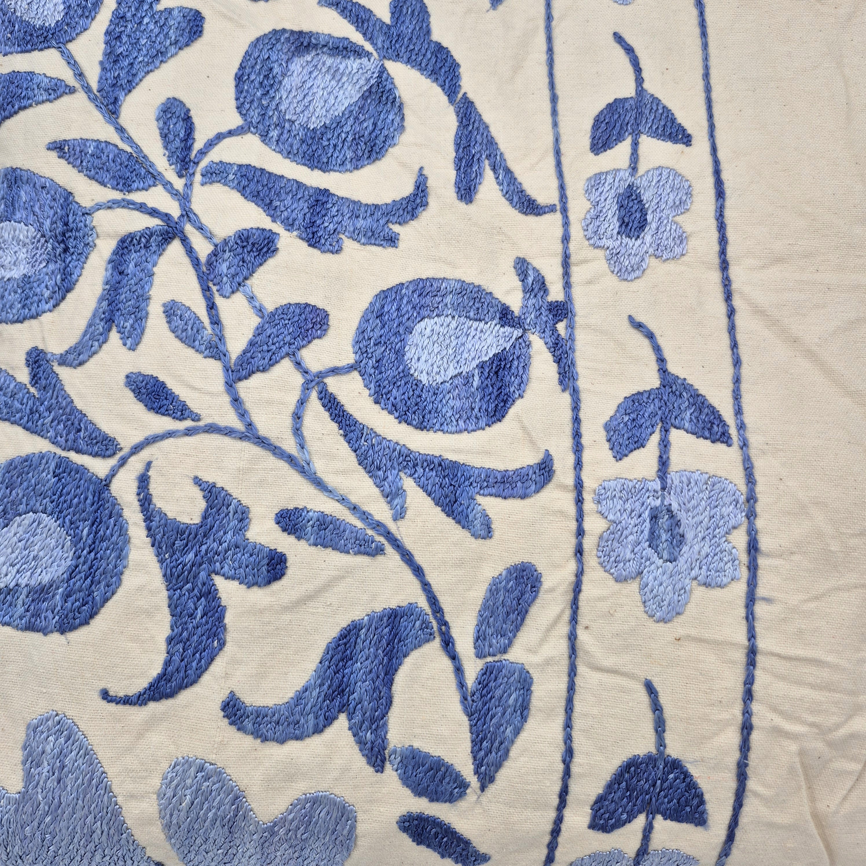 Close-up of blue suzani embroidery on cream fabric