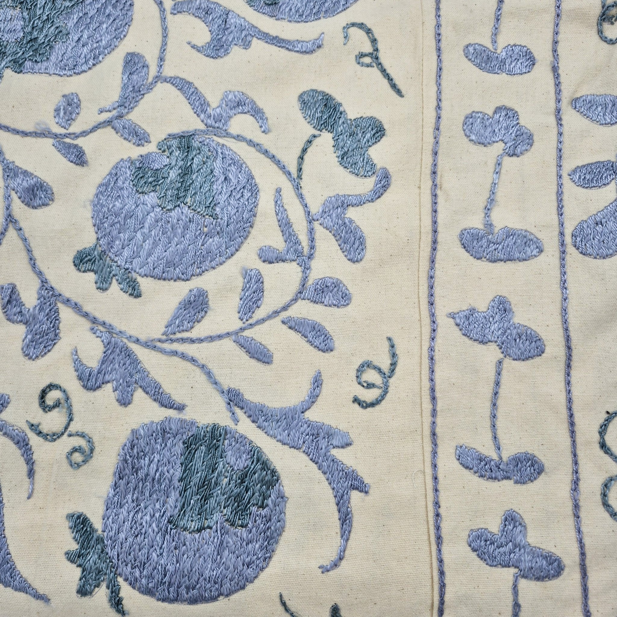 Close-up of blue embroidered suzani fabric on cream background